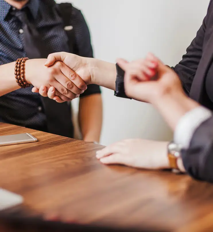 Two people shaking hands across a table